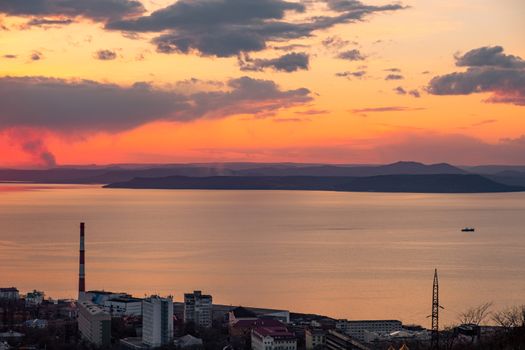 View of the city of Vladivostok from the hill eagle's nest . Sunset. The sky is orange and pink. Sea and city at sunset.