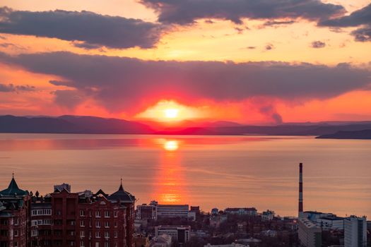 View of the city of Vladivostok from the hill eagle's nest . Sunset. The sky is orange and pink. Sea and city at sunset.