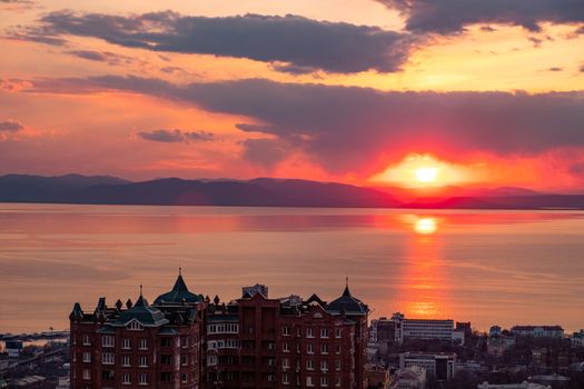 View of the city of Vladivostok from the hill eagle's nest . Sunset. The sky is orange and pink. Sea and city at sunset.