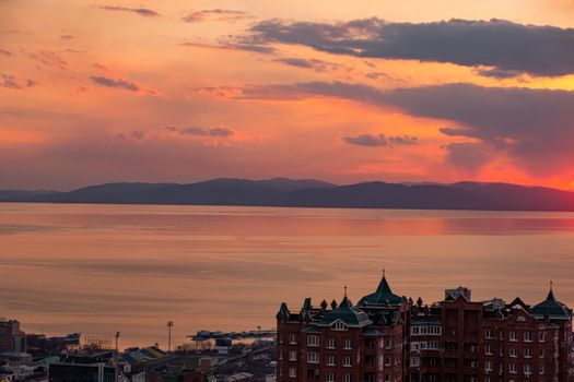 View of the city of Vladivostok from the hill eagle's nest . Sunset. The sky is orange and pink. Sea and city at sunset.