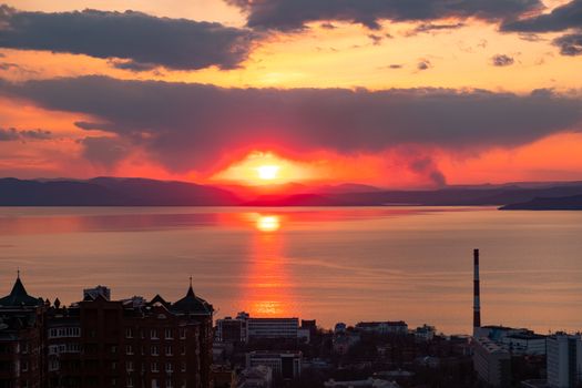 View of the city of Vladivostok from the hill eagle's nest . Sunset. The sky is orange and pink. Sea and city at sunset.