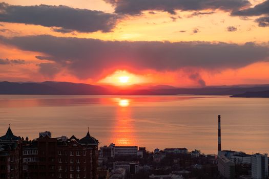 View of the city of Vladivostok from the hill eagle's nest . Sunset. The sky is orange and pink. Sea and city at sunset.