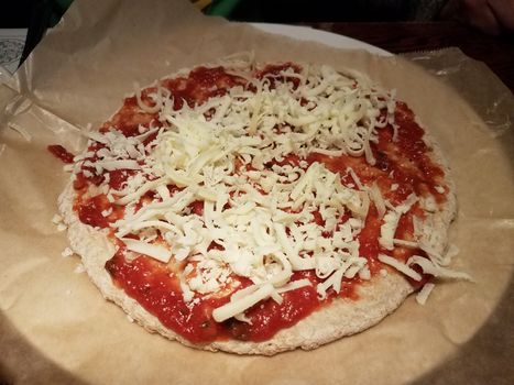 pizza dough and red tomato sauce and cheese on wax paper