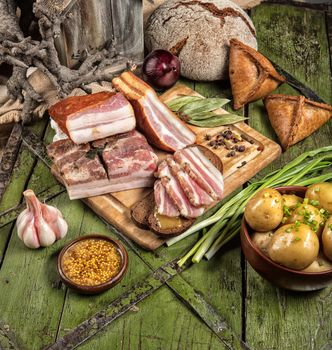 Pices of ham and greenery on a wooden desk