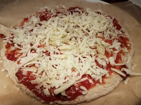 pizza dough and red tomato sauce and cheese on wax paper