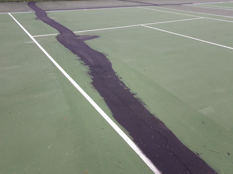 black tar or liquid to repair cracks and damage on green tennis court