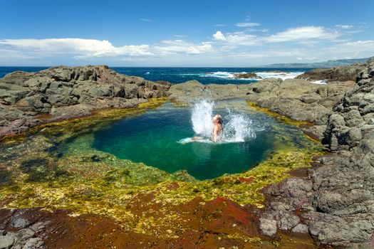 Female makes a splash after jumping into a beautiful rock pool south coast of NSW, Australia