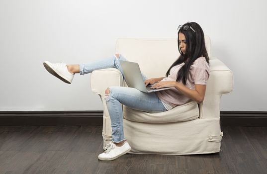 young woman, sitting on a couch, working on a laptop