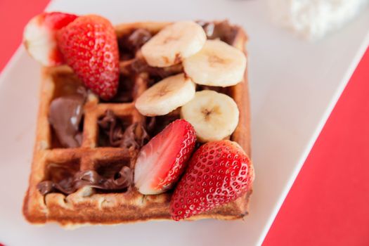 Strawberry and Banana Waffle on red background closeup
