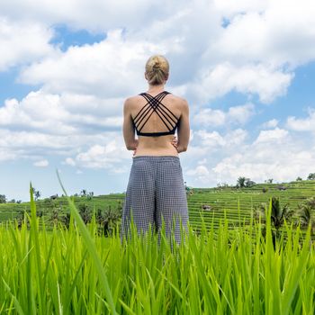 Relaxed sporty female traveler enjoying pure nature at beautiful Jatiluwih rice fields on Bali. Concept of sustainable tourism, nature enjoyment, balanced life, freedom, vacations and well being.