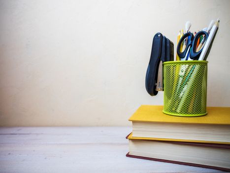 View on the pile of books and cup with pencils lying on the wooden table