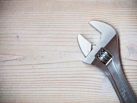 Stainless adjustable spanner on wooden board. Copy space. Plumbing concept