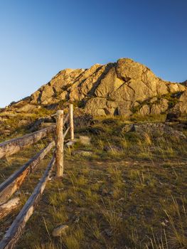 Wooden fence and stone hill in the light of the setting sun