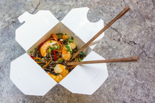 Traditional Chinese takeaway fast food - buckwheat soba noodles with vegetables and shrimps packed in a cardboard box with chopsticks - photo, image,