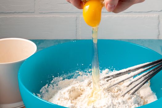 Breaking an egg into flour while preparing the dough - photo, image.