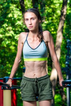 street portrait of a strong woman who poses at the gym in the park during training