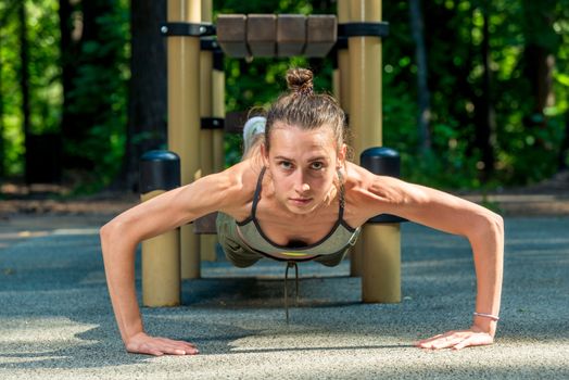 athletic and muscular young girl wrung out, training in the fresh air