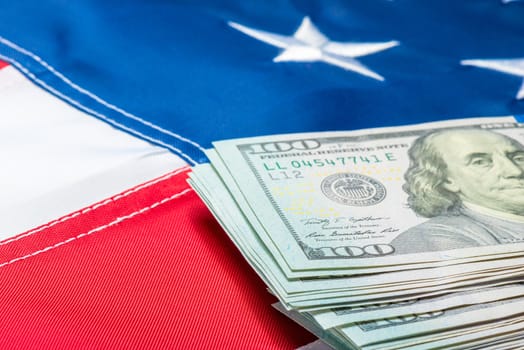 View of a stack of money lying on the flag of the United States of America close-up