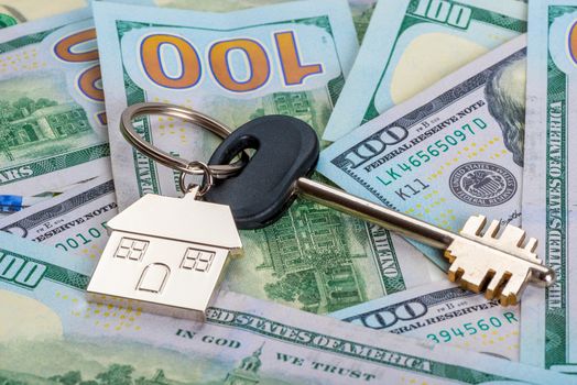 concept photo of money and real estate a key from a new house on a pile of American dollars close up