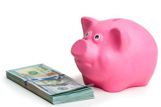 pink piggy bank and pile of american dollars on white background isolated side view