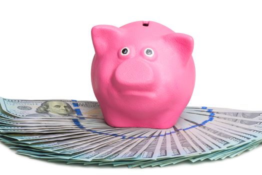 pink piggy bank standing on a fan of a pile of american dollars on a white background isolated