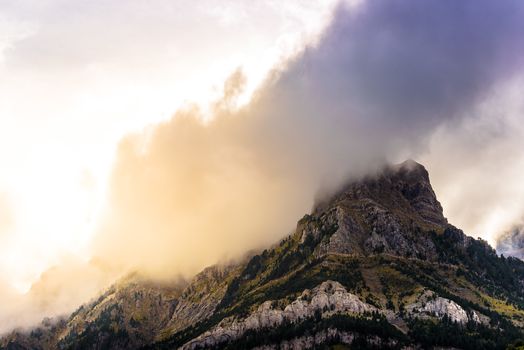 Clouds passing over a mountains, the sun shines orange at sunset