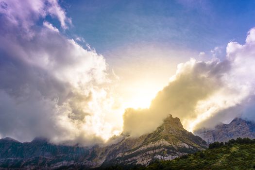 Clouds passing over the mountains, the sun shines at sunset