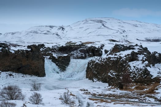 Frozen Hjalparfoss waterfall on a cloudy morning, winter in Iceland, Europe