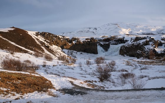 Frozen Hjalparfoss waterfall on a cloudy morning, winter in Iceland, Europe