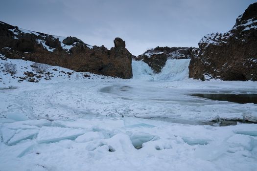 Frozen Hjalparfoss waterfall on a cloudy morning, winter in Iceland, Europe