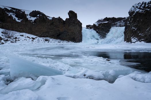 Frozen Hjalparfoss waterfall on a cloudy morning, winter in Iceland, Europe