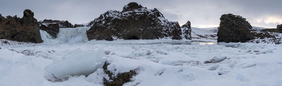 Frozen Hjalparfoss waterfall on a cloudy morning, winter in Iceland, Europe