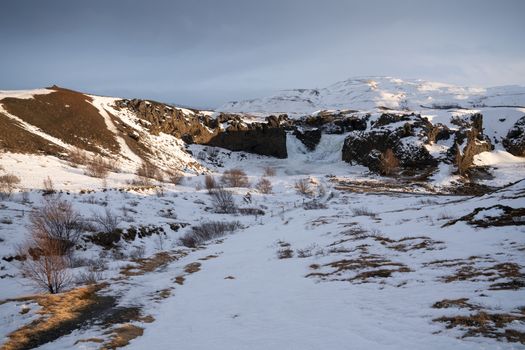 Frozen Hjalparfoss waterfall on a cloudy morning, winter in Iceland, Europe