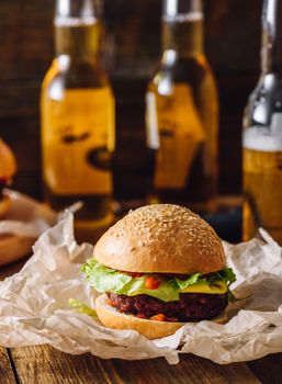 Homemade Cheeseburger on Kraft Paper and Few Bottle of Beer on Background. Vertical Orientation.