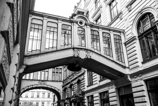 Ornamental bridges between buildings in Nekazanka Street, Prague. Black and white image.