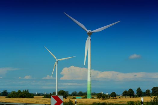 Windmill turbines with partially cloudy blue sky in the background. Wind turbines for renewable energies