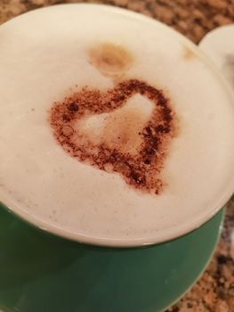 Green cup of coffee with foam and heart