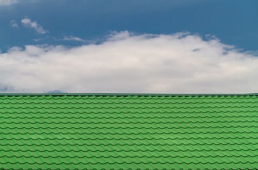 The texture of the roof is green, against the background of the cloudy sky.