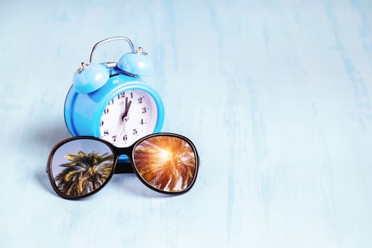 Blue sea background with sunglasses and alarm clocks, summer holiday and vacation time concept.