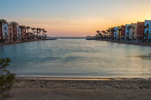 View of a lagoon of the Red Sea at sunrise between two rows of hotel room in Hurghada