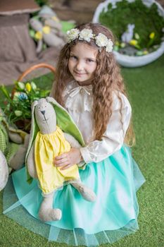Cute little child girl with toy bunny among Easter studio decoration
