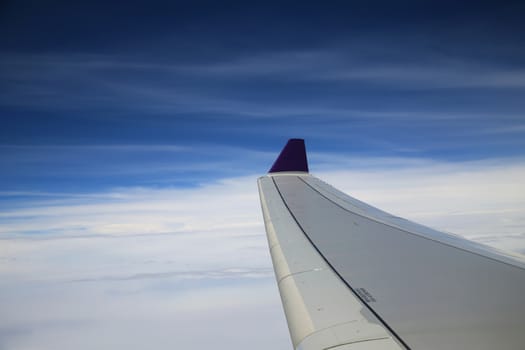 View from airplane window on the wing  over the white cloud and blue sky in the sunny day.