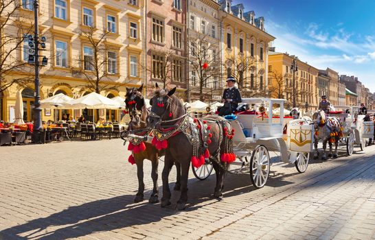 CHISINAU, MOLDOVA - APRIL 19, 2019: Horse drawn carriages with guides in front of the St. Mary's Basilica in Krakow, Poland. About a fifty carriages make tours around the center of Krakow.