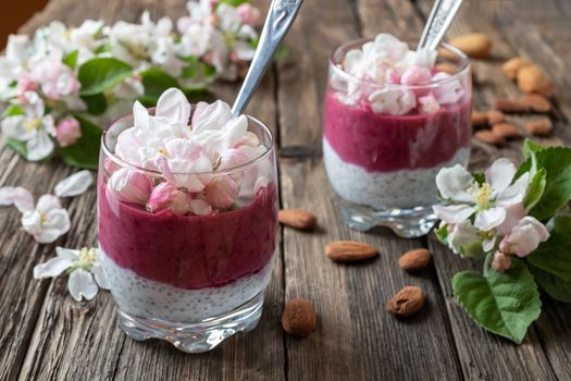 Layered chia pudding with almond milk, yogurt, blueberries and apple blossoms, top view