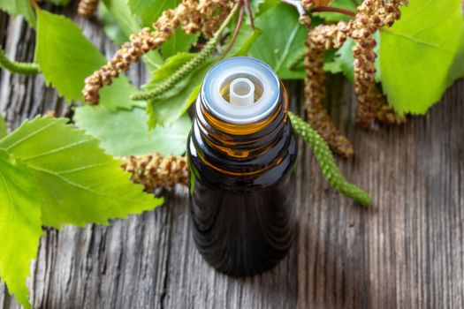 A bottle of essential oil with fresh birch branches