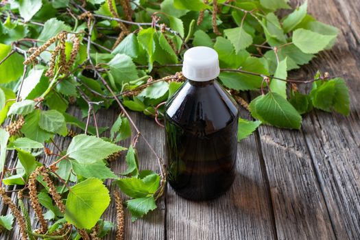 A bottle of tincture with young birch branches