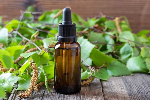 A bottle of essential oil with fresh birch branches