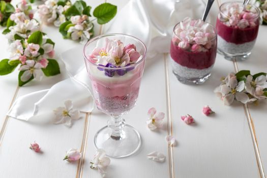Layered chia pudding with yogurt, red currants, blueberries and apple blossoms