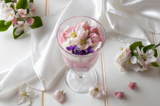 Chia pudding with yogurt, red currants and apple blossoms on a table