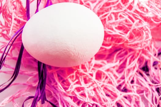 Easter concept, white egg on neon pink background, woven fabric nest, top view, copy space, modern design.